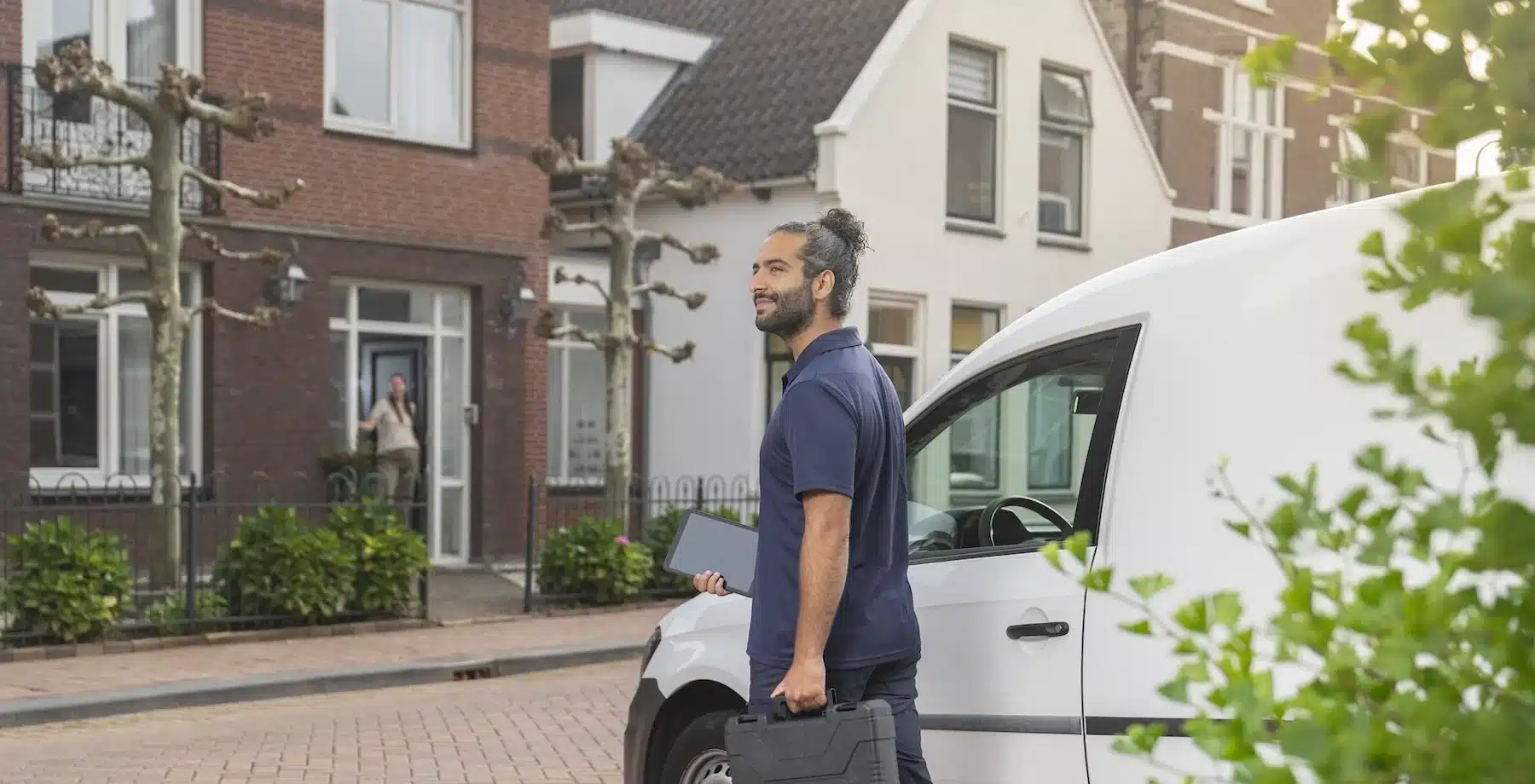 monteur die uit zijn bus stapt en richting het huis van de klant loopt
