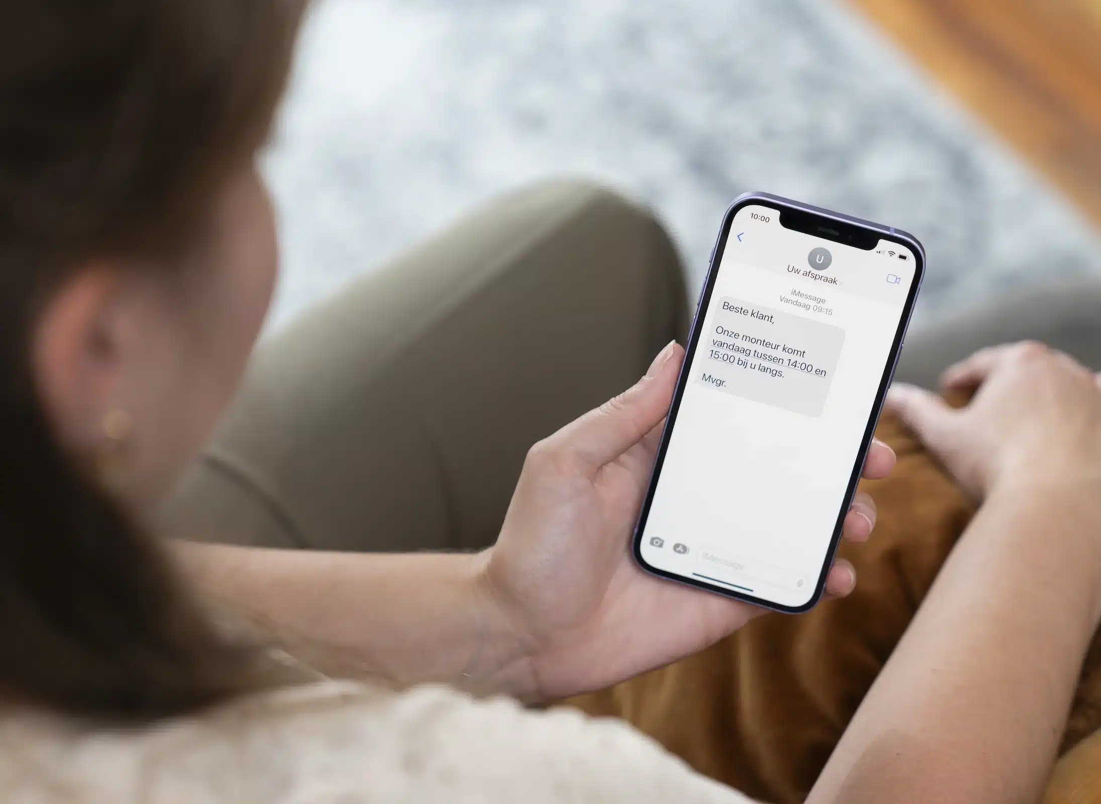 vrouw op de bank die een sms ontvangt
