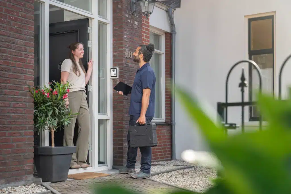 monteur die aankomt bij een vrouw die thuis in de deuropening staat